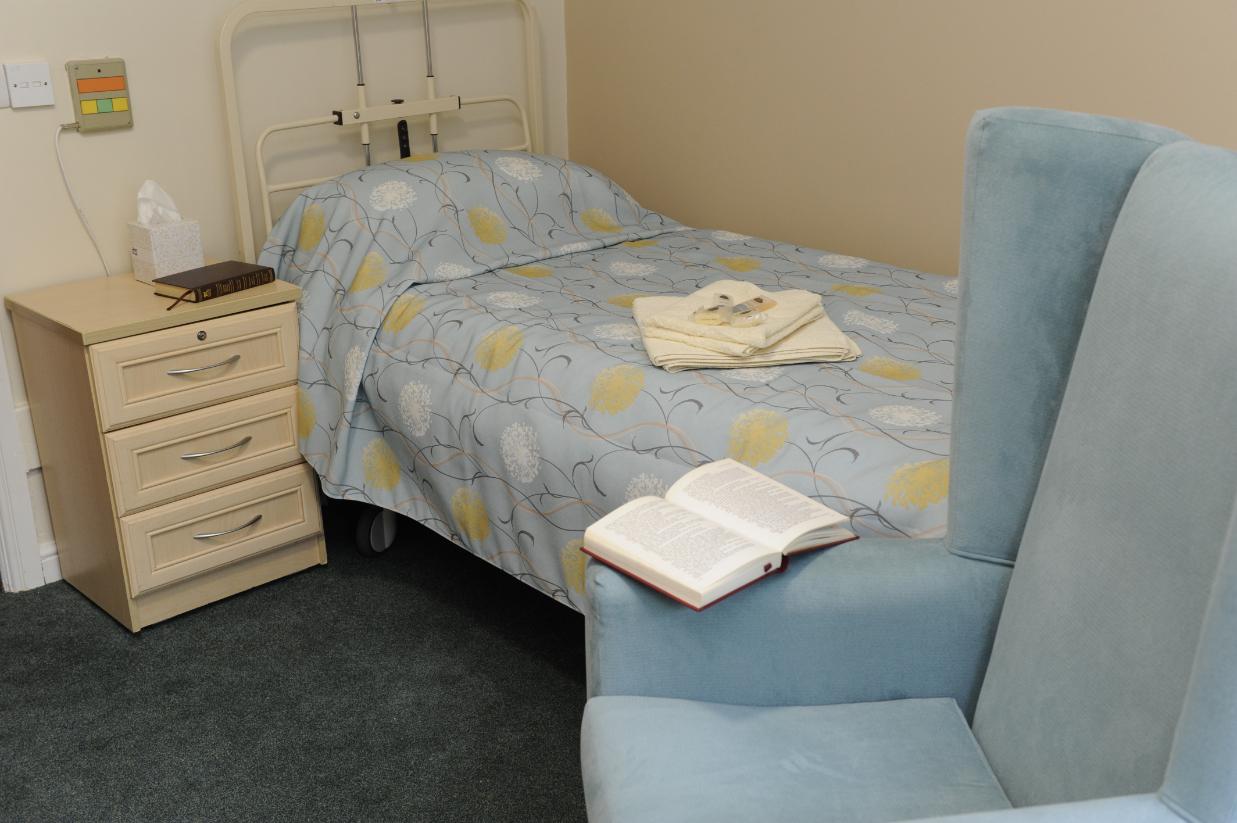 a bed with blue sheets and a blue armchair next to it